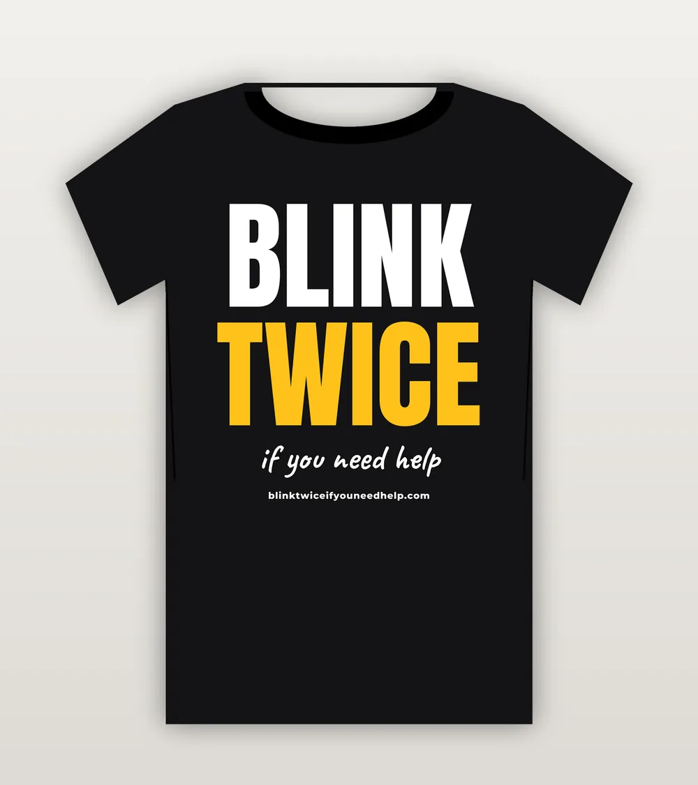 T-shirt printed with BLINK TWICE IF YOU NEED HELP in bold block letters